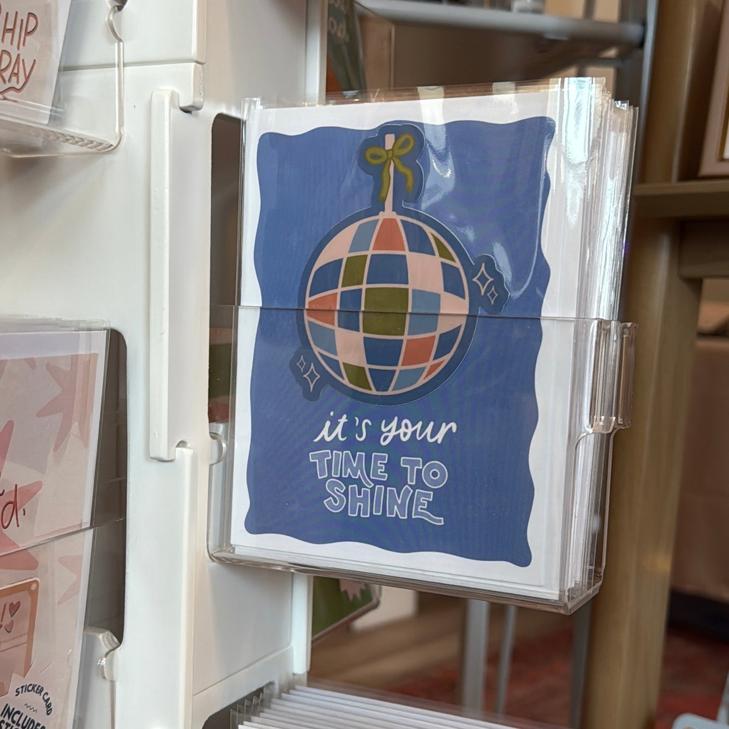 Display of greeting cards with a focus on one card featuring a colorful globe design and text.