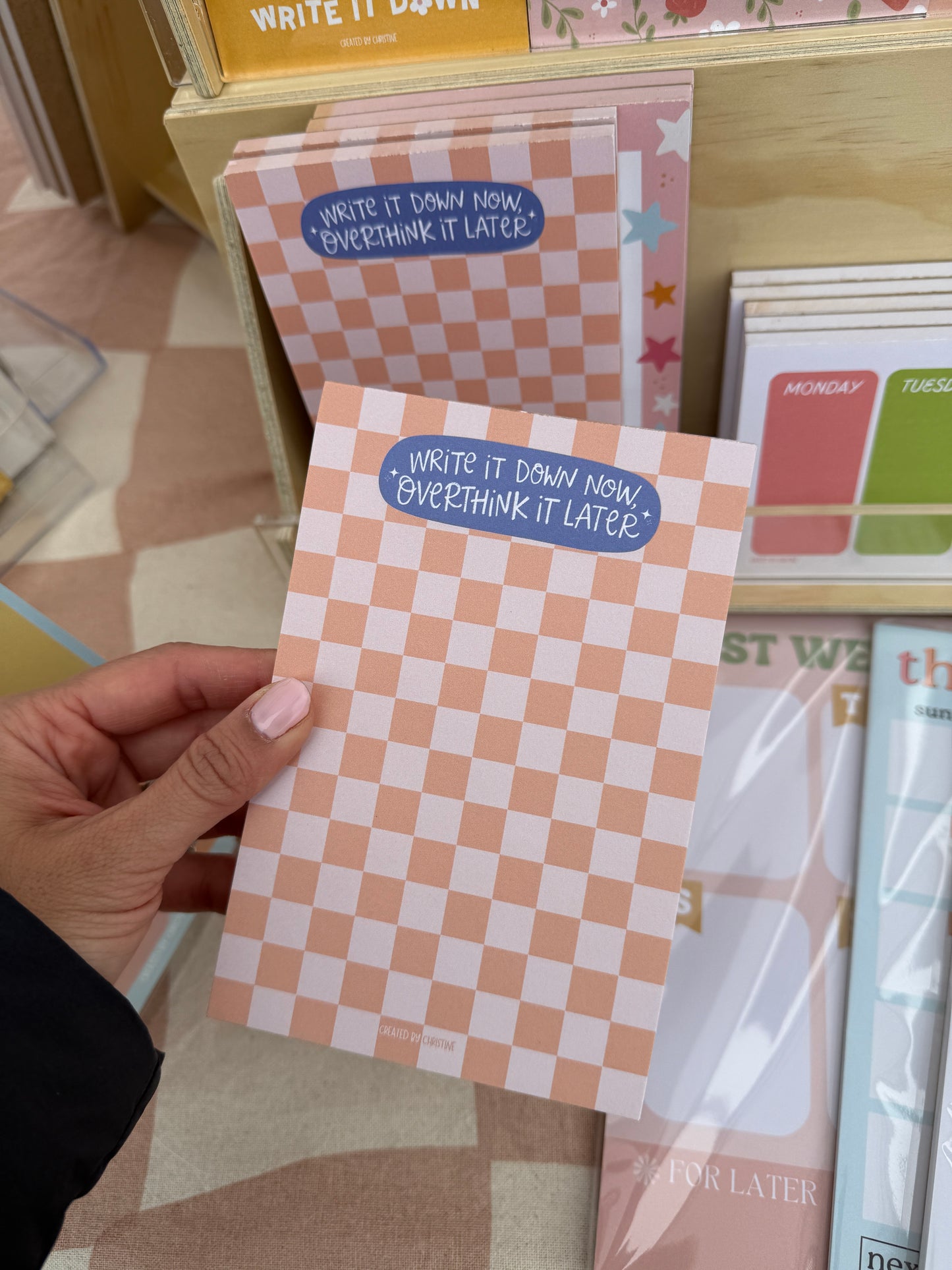 Checkered card with text held by a hand against a background of other cards.
