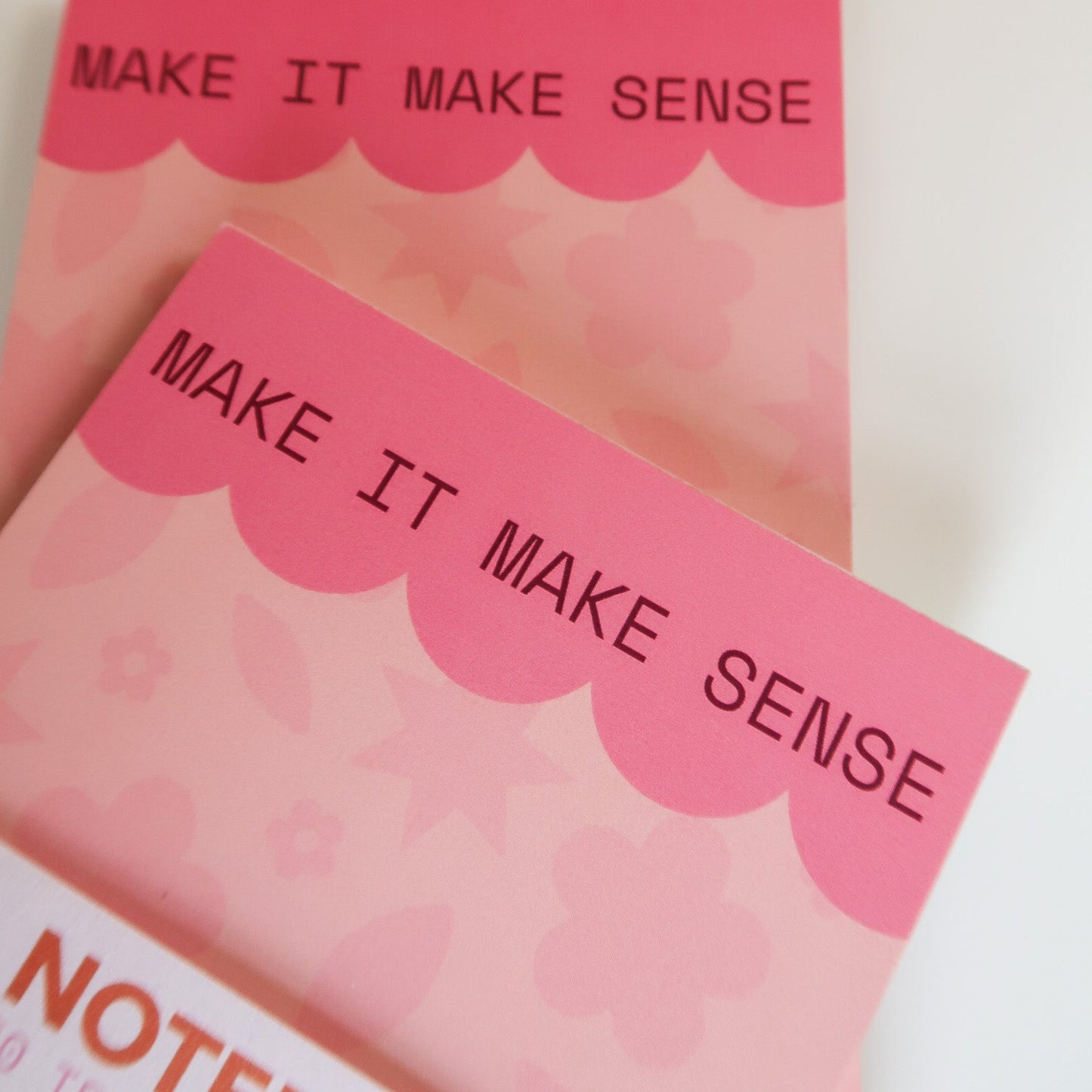 Two pink notepads with 'MAKE IT MAKE SENSE' text on a light background