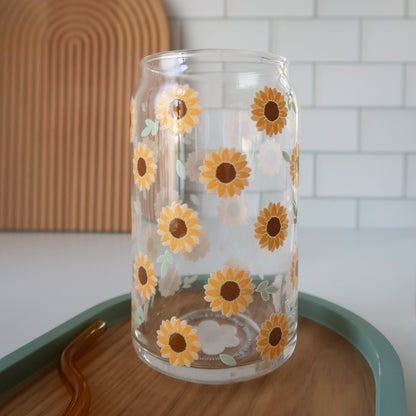 Clear glass with sunflower designs on a wooden surface with a white tiled wall background