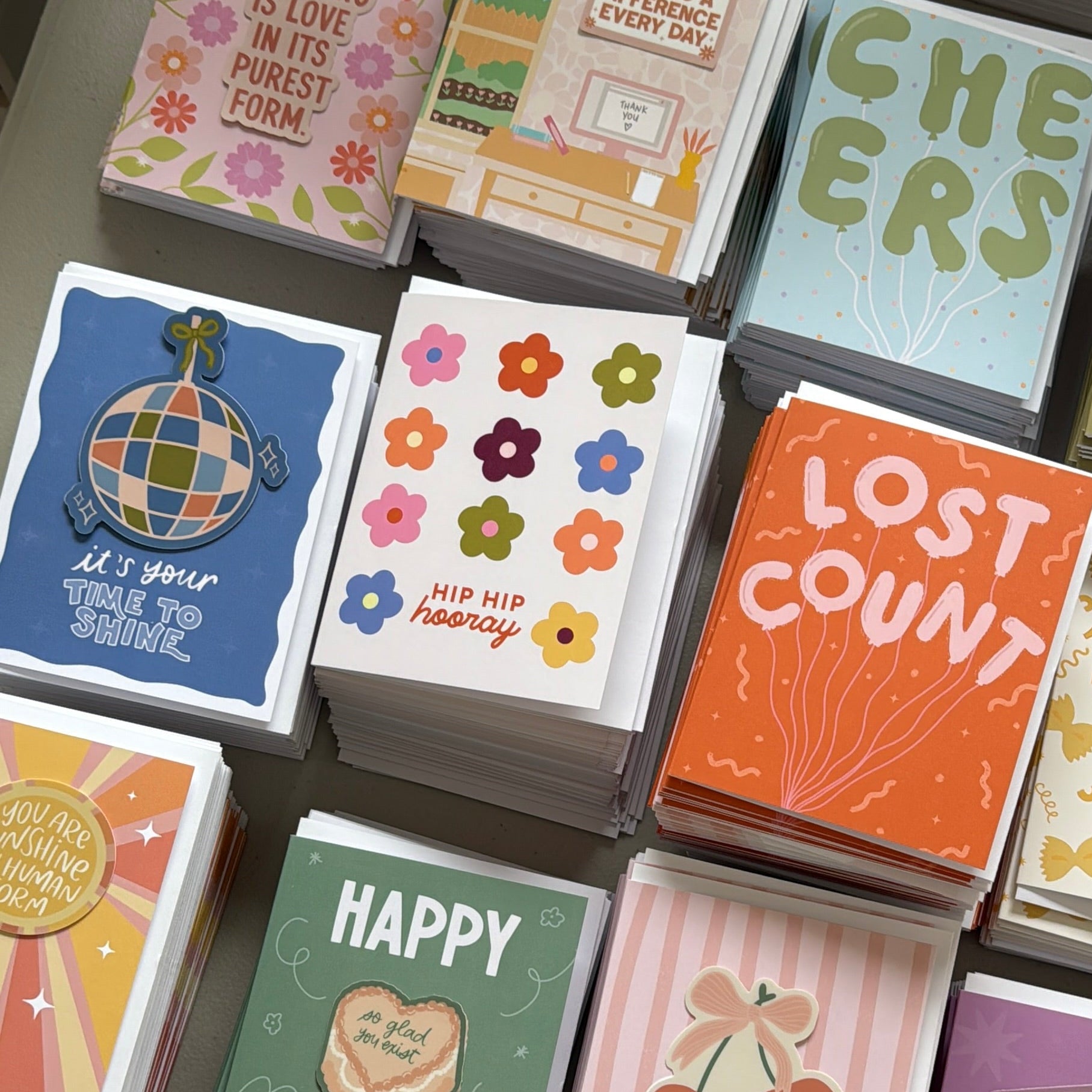 Collection of colorful greeting cards with various designs on a gray surface.