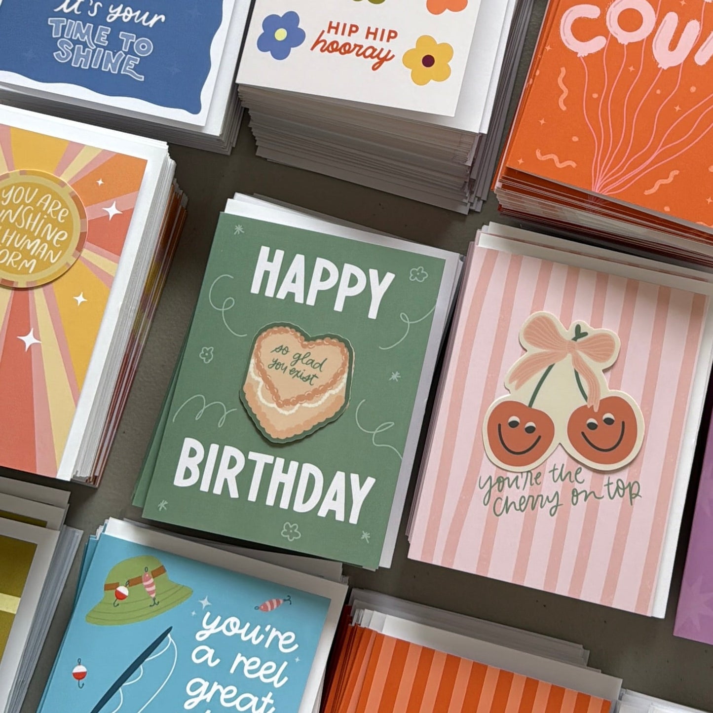 Collection of colorful greeting cards with various designs on a gray surface.