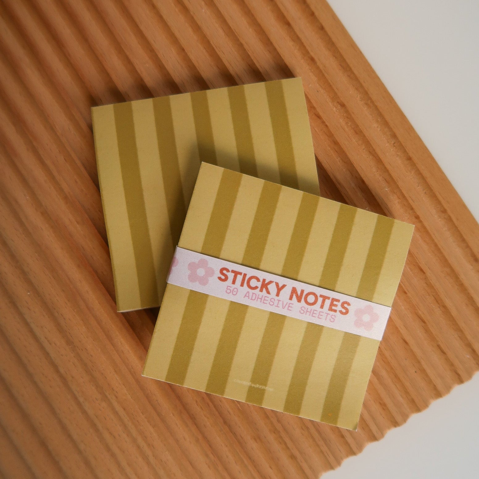 Gold striped sticky notes with a label on a wooden surface