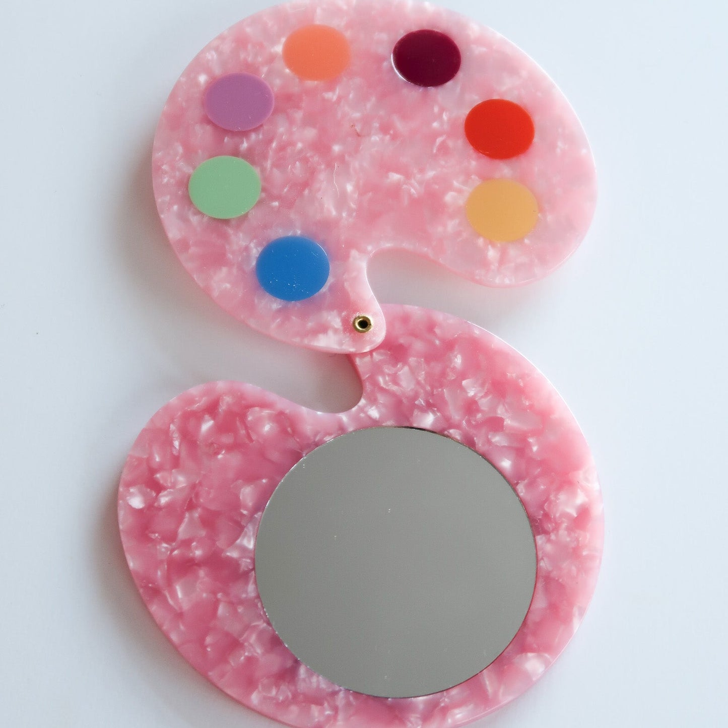 Pink mirror with colorful dot design on a white background