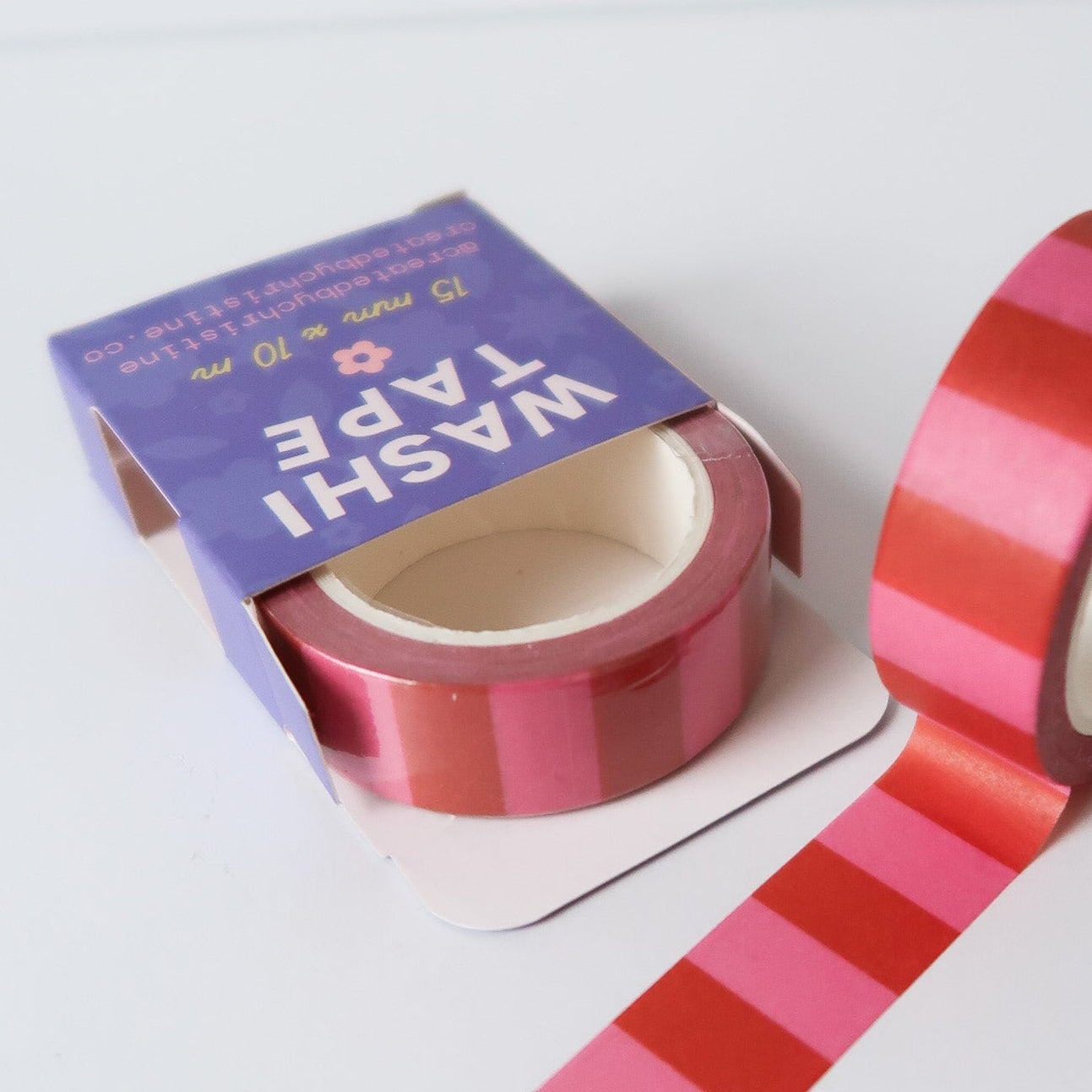Striped washi tape with a purple packaging on a white background